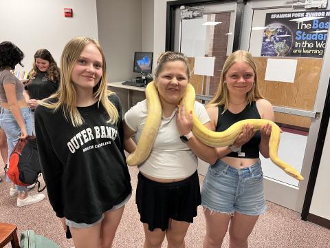 Three students holding a snake